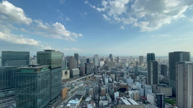UMEDA, OSAKA, JAPAN - JUNE 2024 : Aerial high angle view around Osaka train station in daytime. View of crowded buildings at downtown area. Japanese urban city and business concept video.