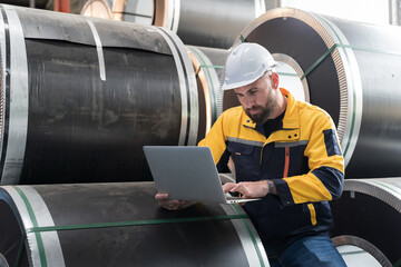 Metalwork manufacturing, warehouse for galvanized or metal sheet. Male engineer worker using laptop...