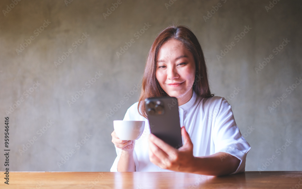 Canvas Prints portrait image of a young woman holding and using mobile phone while drinking coffee