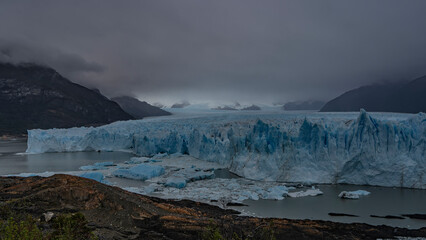 The incredible Perito Moreno glacier stretches between the mountains to the horizon. An endless field of blue ice with cracks, sharp peaks. Thawed ice floes, icebergs float in a turquoise glacial lake