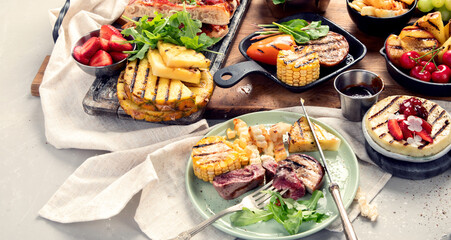 Table with grilled food. Pizza, corn, tomatoes, peppers, cooked meat. BBQ time