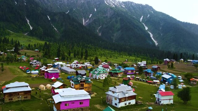 Profile view of colorful houses at Arang Kel town in Kashmir, Pakistan during monsoon. Drone shot.