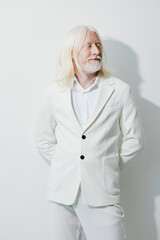 Portrait of a senior man with long white hair dressed in a white suit against a minimalist light background, exuding elegance and confidence in a professional setting