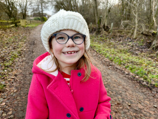 Portrait of a cute school girl with eyeglasses outdoors in park. Happy funny child on autumn, spring or winter day.