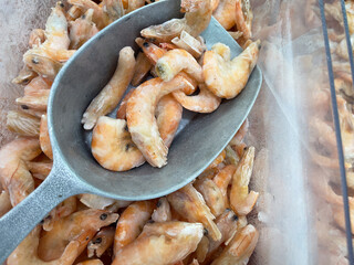 Frozen shrimp in a ladle on the store counter.