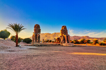 View of the Colossi of Memnon, stone statues of the Pharaoh Amenhotep III, at the ruined Mortuary Temple of Amenhotep III, the largest temple in the Theban Necropolis,1350 BC in Luxor,Egypt 