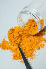 Turmeric powder in a jar on a light background