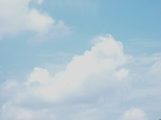 This image depicts a clear blue sky with white, wispy clouds. The sky is a vibrant blue color, contrasting with the lighter tones of the clouds. The clouds are thin and delicate, creating a sense of o