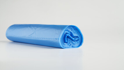 Blue polyethylene garbage bags packed in a roll on a white background. Cleaning products for home or office. Photo. Selective focus. Copy space