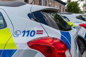 Fleet of police cars parked outside a station with visible emergency contact details.