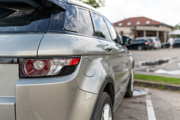 A parked silver SUV in a public lot near a restaurant on a sunny day