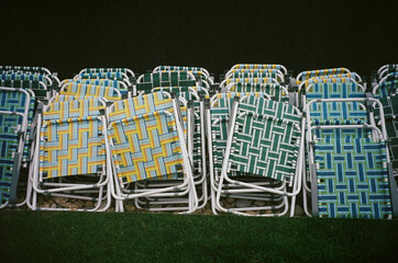 A stack of vintage lawn chairs with colorful woven patterns