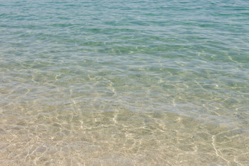 Clear shallow seawater with gentle ripples over sandy bottom