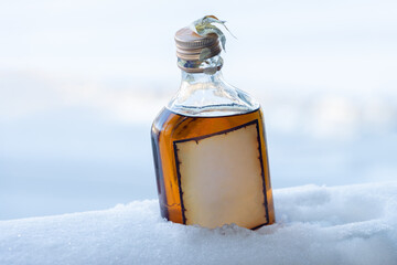 A small bottle of spirit stands on the snowy railing