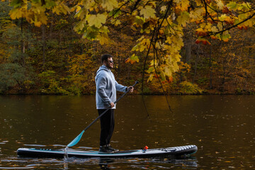 Man Paddleboarding in Autumn Lake