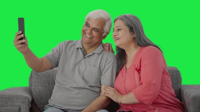 Happy Indian old couple clicking selfies Green screen