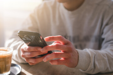 Social media marketing concept. Man hand using smartphone typing, chatting conversation in chat box icons pop up checking social media in cafe having a relaxing momen