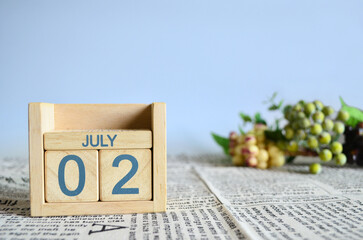 July 2, Calendar cover design with number cube with fruit on newspaper fabric and blue background.