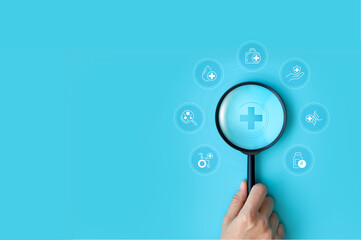 Hand holding magnifying glass focus plus and healthcare medical icon on blue background. health insurance concept and access to welfare. medical technology.