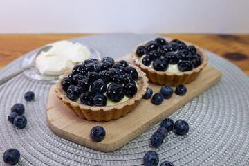 Blueberry tartlets on a small cutting board. blueberries around, mint leaves in between and mascarpone 