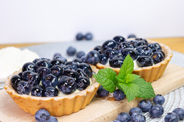 Close-up Blueberry tartlets on a small cutting board. blueberries around and mascarpone on the back