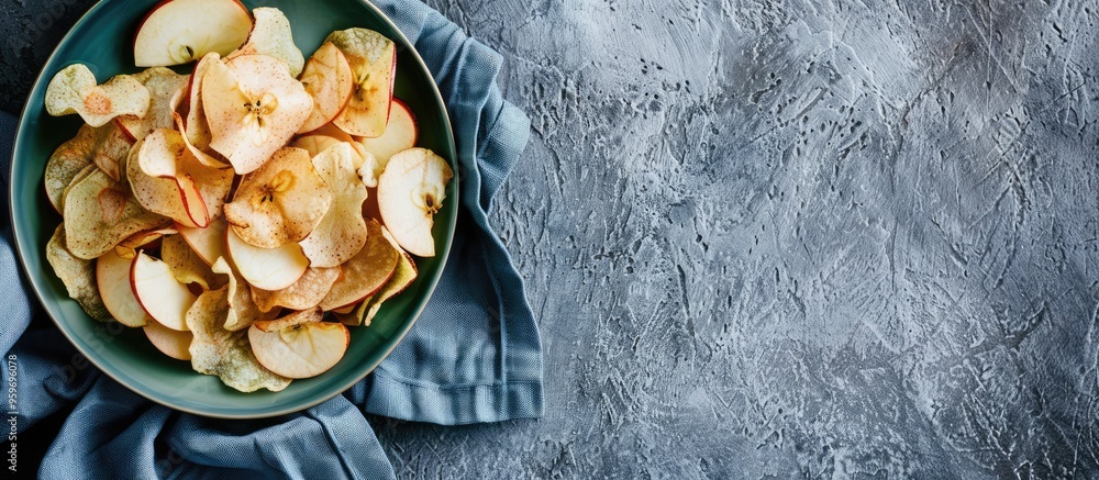 Poster healthy apple chips on a round green plate with a blue cotton kitchen towel on a grey background. wi