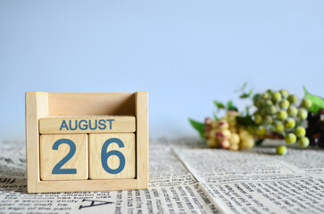 August 26, Calendar cover design with number cube with fruit on newspaper fabric and blue background.	
