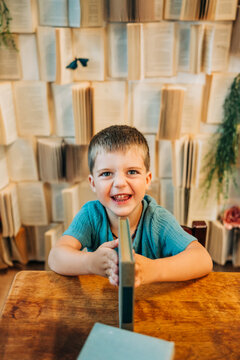 Smiling young boy sitting at a wooden desk with a book