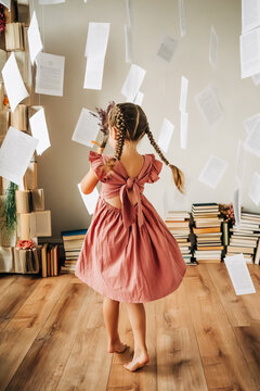 dancing girl with braids in a pink dress surrounded by floating pages