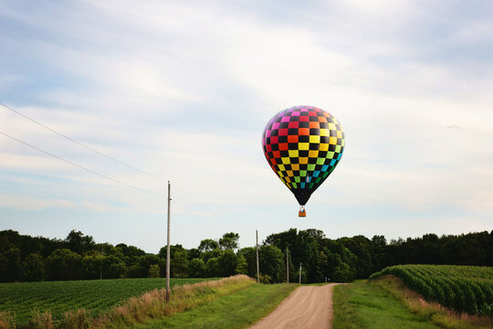 Hot air balloon flying low over a country gravel road.