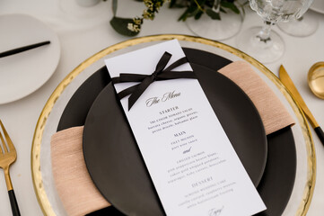 Close up of wedding place setting with black plates and menu
