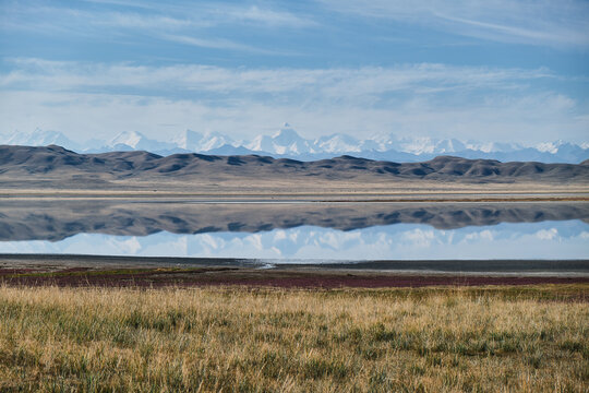 Serene landscape with lake and mountains reflecting in water.