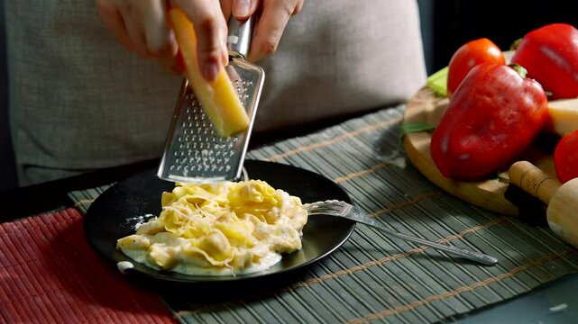 Chef grating cheese over fresh pasta in cozy kitchen