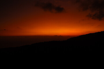 Sunset behind clouds and silhouetted hills