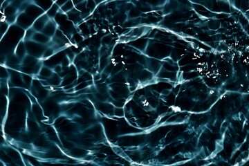 Black water with ripples on the surface. Defocus blurred transparent blue colored clear calm water surface texture with splashes and bubbles. Water waves with shining pattern texture background