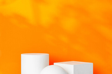 White geometric shapes on a vibrant orange background with soft shadows in a well-lit indoor setting