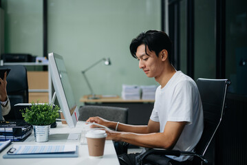 Young business man working at office with laptop, tablet and taking notes on the paper.