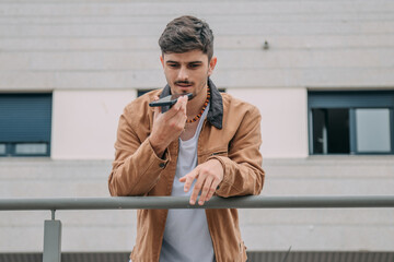 Casual young man using mobile phone to send voice message