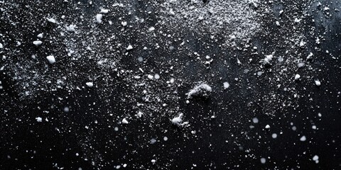 Obraz premium Abstract black background with delicate snowflakes or powdery particles falling and scattering, creating a wintery and textured visual perfect for holiday designs, festive presentations, or creative p