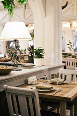 Christmas light modern interior of the restaurant with greenery with pleasant cozy lighting and festive table setting with glasses.