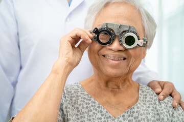 Asian senior woman wearing ophthalmic vision eye test and using optical trial frame.