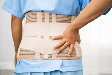 Asian lady patient wearing back pain support belt for orthopedic lumbar with walker.