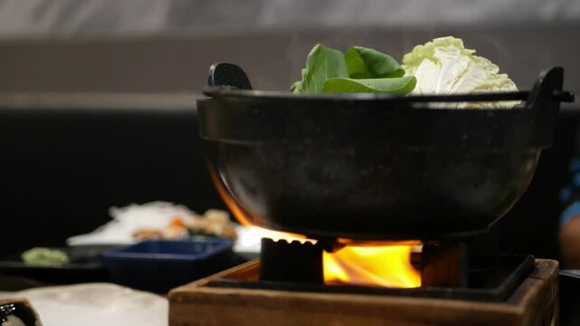 Pov to personal hotpot for japanese shabu shabu while boiling on personal stove in japanese restaurant fot hotpot cooking beef sliced and vegetable,asian food 