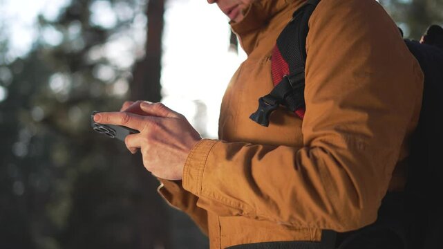 Tourist with smartphone uses map for guidance in dense forest. Map aids in thrilling journey, ensuring safe exploration. Journey enhanced by map tourist confidently navigates woods. Tourist in nature