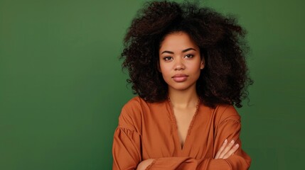 Obraz premium Confident woman with voluminous hair wearing a vintage top, posing against a green background.