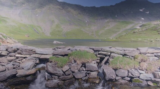 View of a lake with the start of a river in Lake of Fenetre in Valais, Switzerland in the Swiss Alps.