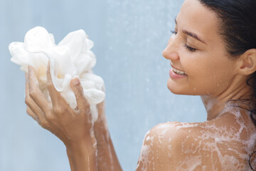 Woman Smiling While Washing with Loofah in Relaxing Shower