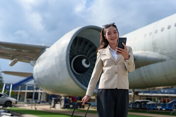 Asian businesswoman arrives at her destination with her suitcase in tow, waiting for her car at the...