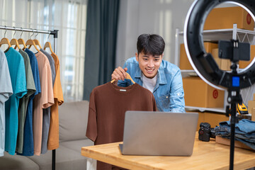 Young Asian man online shop entrepreneur, small business owner live streaming online sales in warehouse