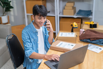 Young Asian man, distributor, online shop owner, small business owner, standing in warehouse and preparing to ship goods, with parcel boxes.